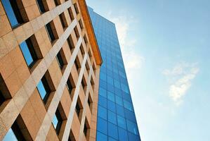 Structural glass wall reflecting blue sky. Abstract modern architecture fragment. photo