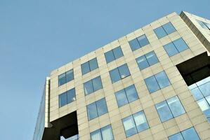 Structural glass wall reflecting blue sky. Abstract modern architecture fragment. photo