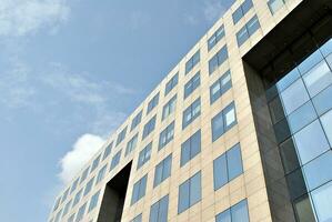 Structural glass wall reflecting blue sky. Abstract modern architecture fragment. photo