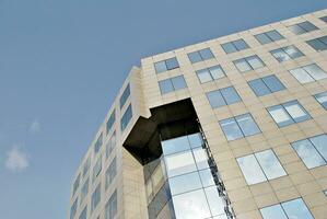 Structural glass wall reflecting blue sky. Abstract modern architecture fragment. photo