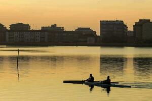 two people rowing on a lake at sunset photo