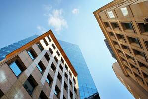 Structural glass wall reflecting blue sky. Abstract modern architecture fragment. photo