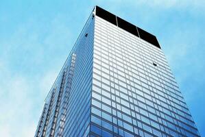 Structural glass wall reflecting blue sky. Abstract modern architecture fragment photo