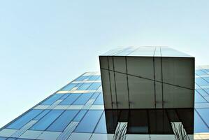 Structural glass wall reflecting blue sky. Abstract modern architecture fragment photo