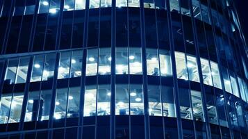 Pattern of office buildings windows illuminated at night. Glass architecture ,corporate building at night - business concept. Blue graphic filter. photo