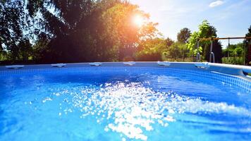 Swimming pool with metal frame for home and garden. Frame swimming pool in the yard. Garden in the background. Summer holiday fun and recreation. photo