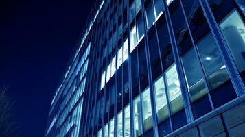 Pattern of office buildings windows illuminated at night. Glass architecture ,corporate building at night - business concept. Blue graphic filter. photo