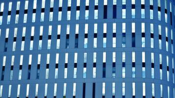 Pattern of office buildings windows illuminated at night. Glass architecture ,corporate building at night - business concept. Blue graphic filter. photo