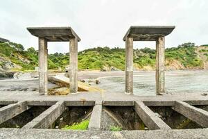 two concrete pillars on the beach near the water photo