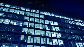 Pattern of office buildings windows illuminated at night. Glass architecture ,corporate building at night - business concept. Blue graphic filter. photo