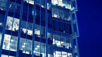 Pattern of office buildings windows illuminated at night. Glass architecture ,corporate building at night - business concept. Blue graphic filter. photo