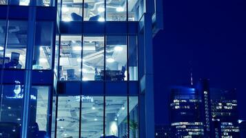 Pattern of office buildings windows illuminated at night. Glass architecture ,corporate building at night - business concept. Blue graphic filter. photo