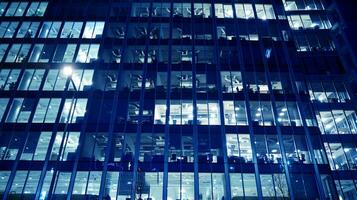 Pattern of office buildings windows illuminated at night. Glass architecture ,corporate building at night - business concept. Blue graphic filter. photo