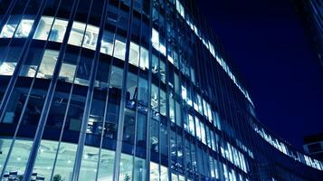Pattern of office buildings windows illuminated at night. Glass architecture ,corporate building at night - business concept. Blue graphic filter. photo