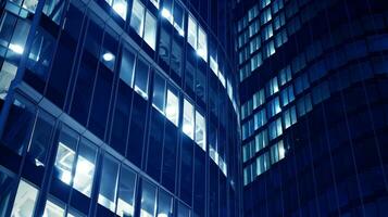 Pattern of office buildings windows illuminated at night. Glass architecture ,corporate building at night - business concept. Blue graphic filter. photo