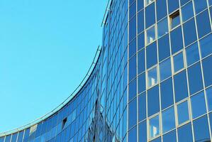 Structural glass wall reflecting blue sky. Abstract modern architecture fragment photo