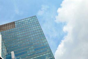 Structural glass wall reflecting blue sky. Abstract modern architecture fragment photo