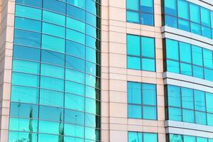 Structural glass wall reflecting blue sky. Abstract modern architecture fragment photo