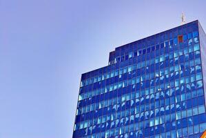 Structural glass wall reflecting blue sky. Abstract modern architecture fragment photo