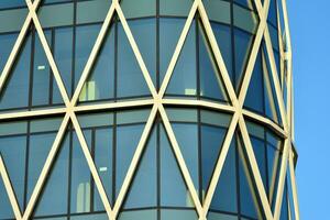 Structural glass wall reflecting blue sky. Abstract modern architecture fragment photo