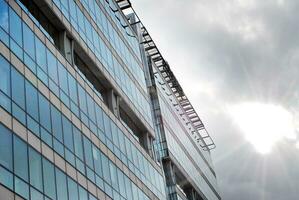 Structural glass wall reflecting blue sky. Abstract modern architecture fragment. photo