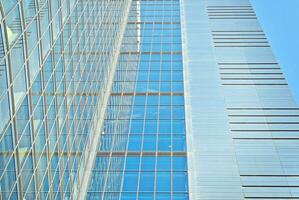 Structural glass wall reflecting blue sky. Abstract modern architecture fragment photo