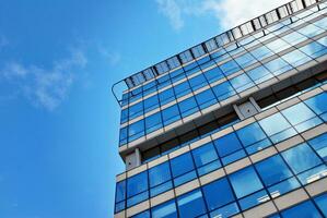 Structural glass wall reflecting blue sky. Abstract modern architecture fragment. photo