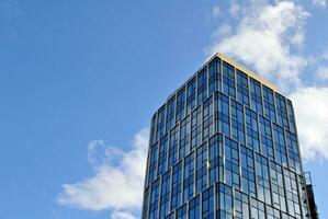 Structural glass wall reflecting blue sky. Abstract modern architecture fragment. photo