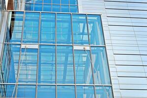 Structural glass wall reflecting blue sky. Abstract modern architecture fragment. photo