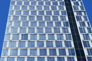 Structural glass wall reflecting blue sky. Abstract modern architecture fragment photo