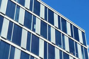 Structural glass wall reflecting blue sky. Abstract modern architecture fragment. photo