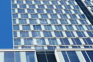 Structural glass wall reflecting blue sky. Abstract modern architecture fragment photo