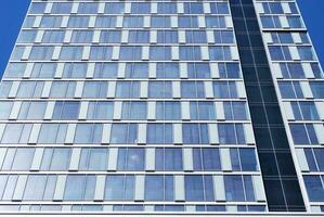Structural glass wall reflecting blue sky. Abstract modern architecture fragment photo