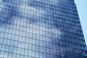 Structural glass wall reflecting blue sky. Abstract modern architecture fragment photo
