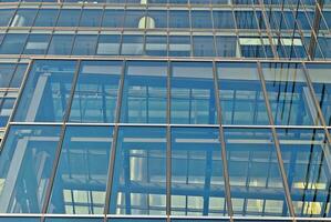 Structural glass wall reflecting blue sky. Abstract modern architecture fragment photo