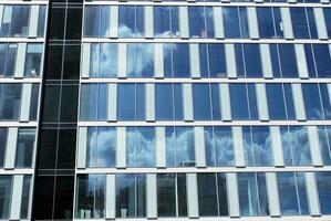 Structural glass wall reflecting blue sky. Abstract modern architecture fragment photo