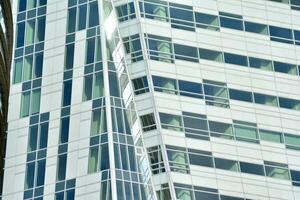 Structural glass wall reflecting blue sky. Abstract modern architecture fragment. photo