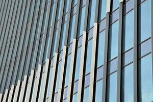 Structural glass wall reflecting blue sky. Abstract modern architecture fragment. photo