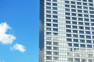 Structural glass wall reflecting blue sky. Abstract modern architecture fragment. photo