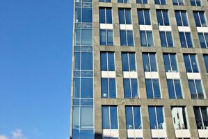 Structural glass wall reflecting blue sky. Abstract modern architecture fragment. photo