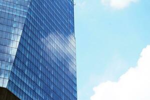 Structural glass wall reflecting blue sky. Abstract modern architecture fragment. photo