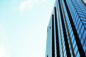 Structural glass wall reflecting blue sky. Abstract modern architecture fragment. photo