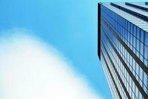 Structural glass wall reflecting blue sky. Abstract modern architecture fragment. photo