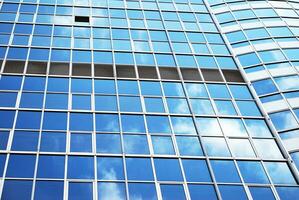 Structural glass wall reflecting blue sky. Abstract modern architecture fragment. photo