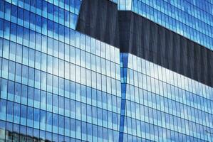 Structural glass wall reflecting blue sky. Abstract modern architecture fragment. photo