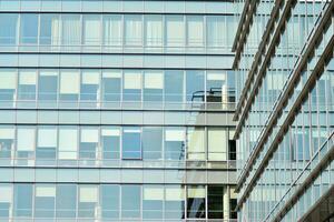 Structural glass wall reflecting blue sky. Abstract modern architecture fragment. photo