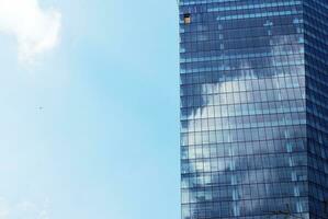 Structural glass wall reflecting blue sky. Abstract modern architecture fragment. photo