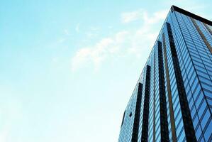 Structural glass wall reflecting blue sky. Abstract modern architecture fragment. photo