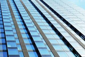 Structural glass wall reflecting blue sky. Abstract modern architecture fragment. photo