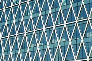 Structural glass wall reflecting blue sky. Abstract modern architecture fragment. photo